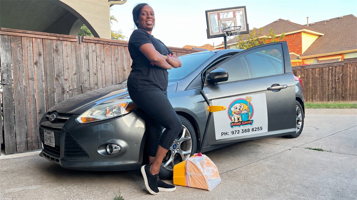 Dee Reed of Poop Savvy leaning on the gray Poop Savvy car with scoop tools